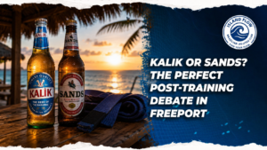 Kalik and Sands beers on a beachside table with a Brazilian Jiu-Jitsu belt, promoting the post "Kalik or Sands? The Perfect Post-Training Debate in Freeport."